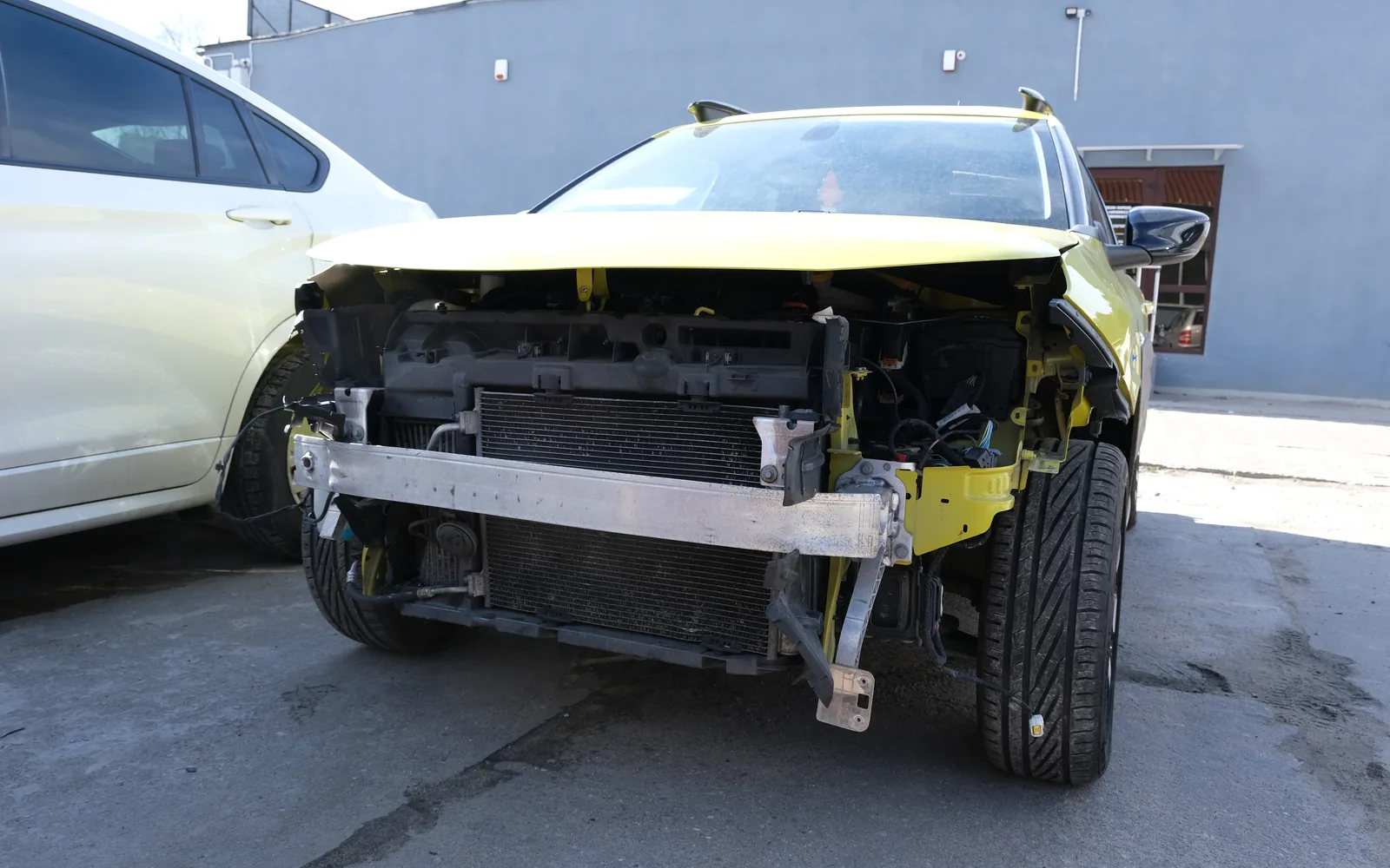 Samochód po kolizji z rozebranym przodem, widoczna chłodnica i wzmocnienie