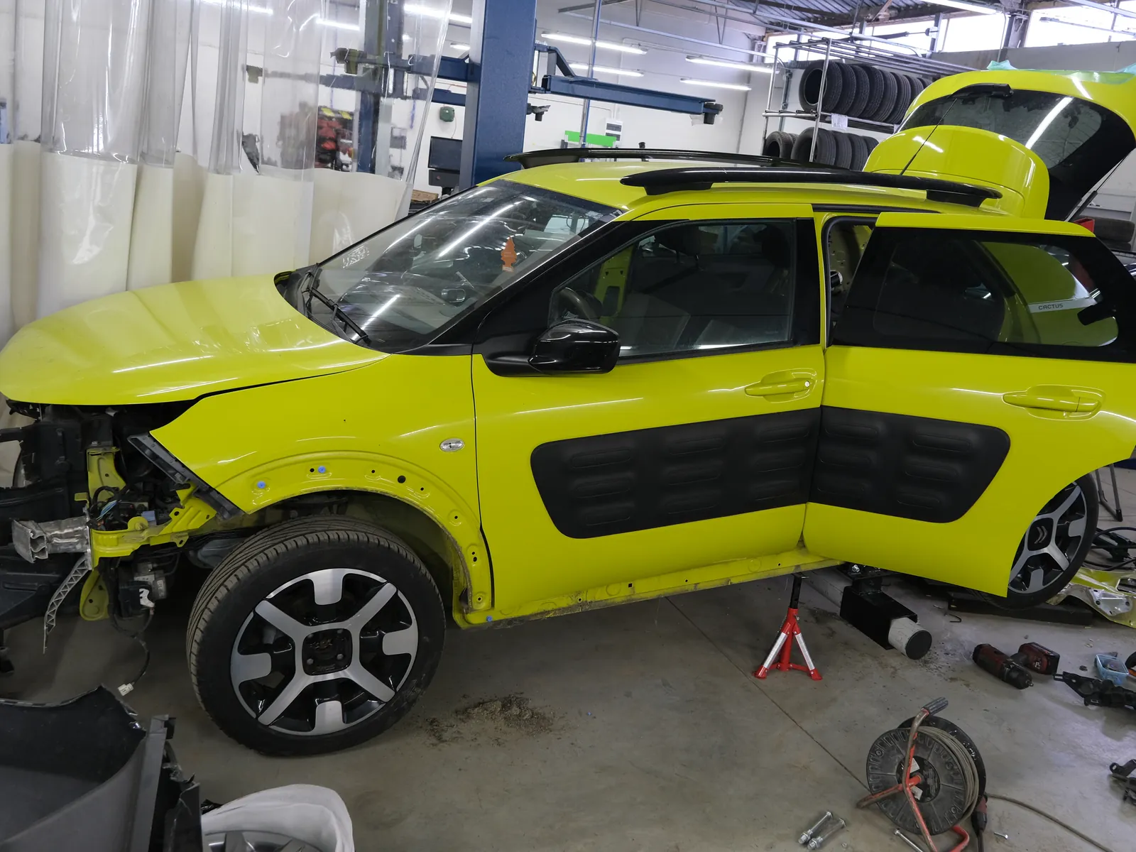 Hala blacharska Bryksacar: żółty Citroen C4 Cactus z rozebranym przodem na stanowisku naprawy powypadkowej, obok zdjęte elementy i podpory