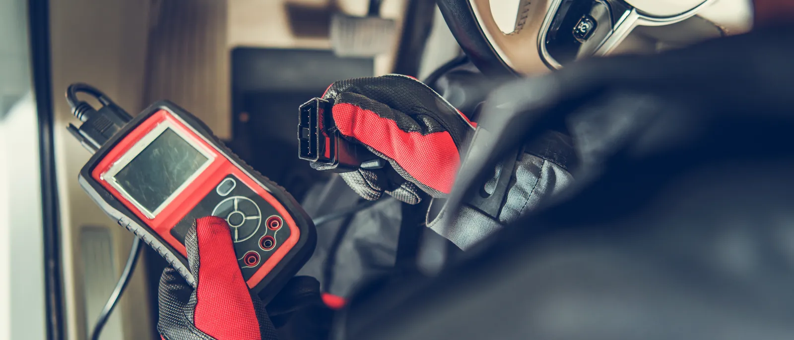 Tester diagnostyczny podpięty do gniazda OBD w aucie