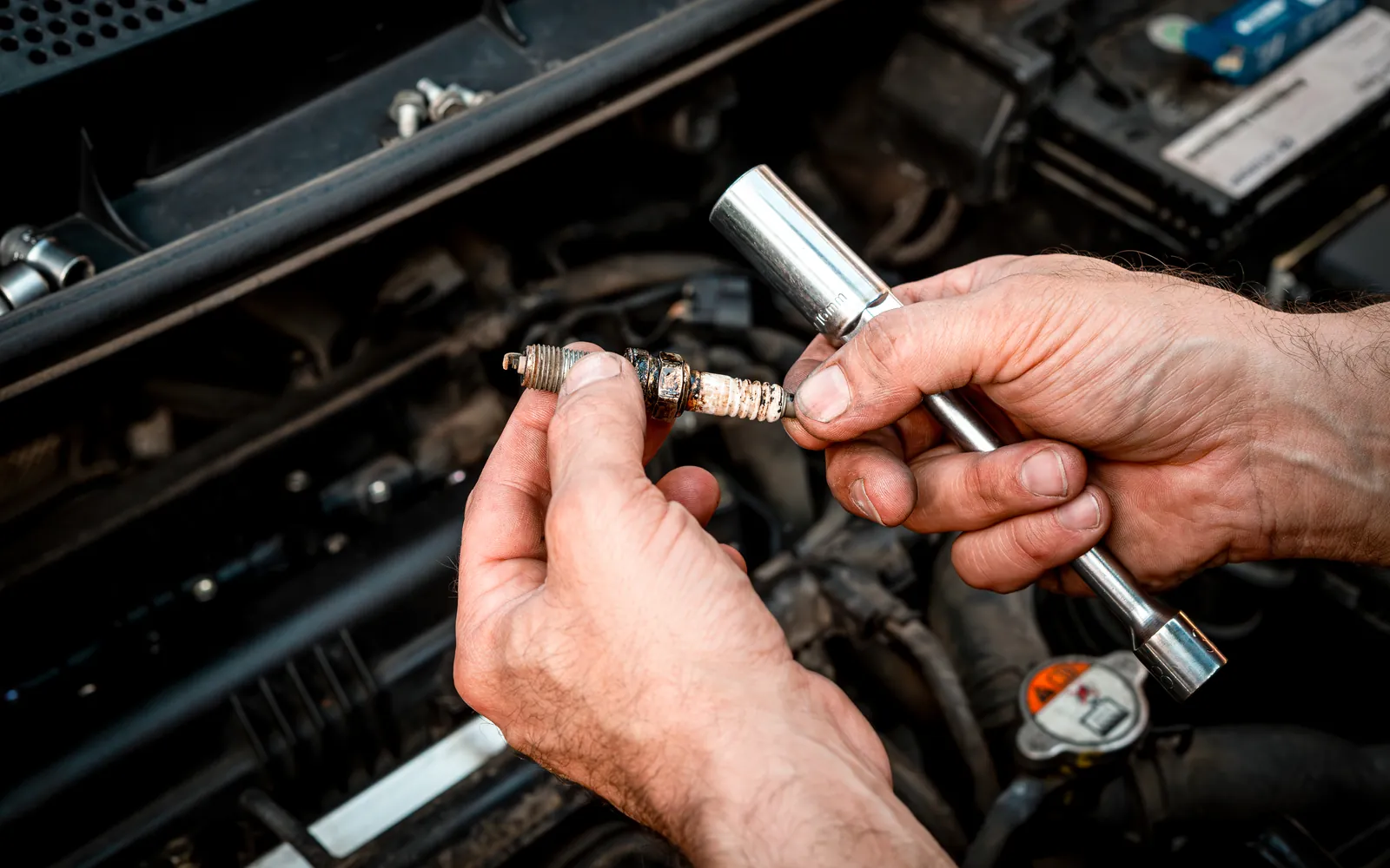 Mechanik trzyma tester diagnostyczny nad komorą silnika