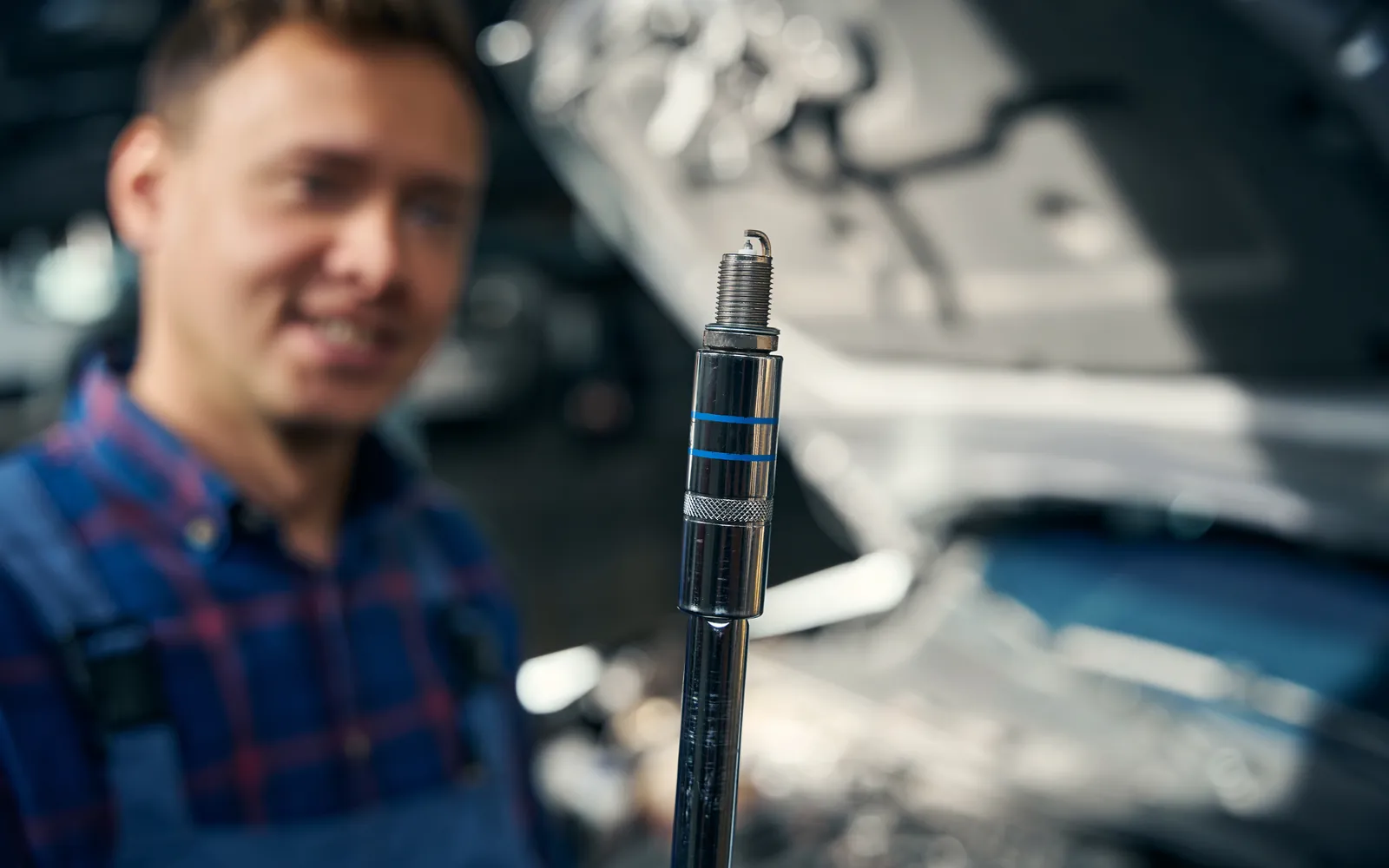 Mechanik trzyma tester diagnostyczny nad komorą silnika